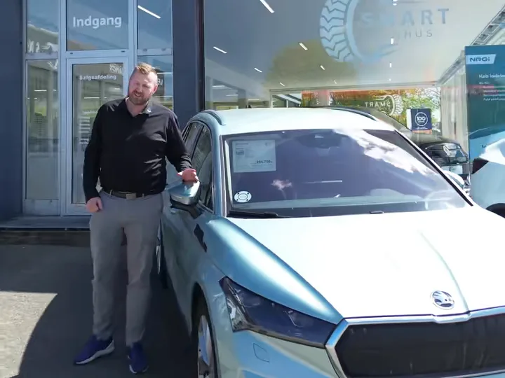 Sælger fra Smart Autohus ved en Skoda Enyaq foran forretningen